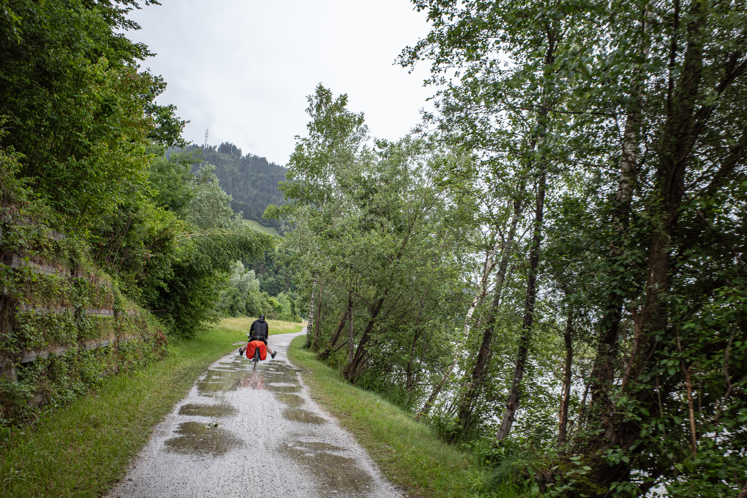 Nasser Schotterweg an der Salzach – die Regenhülle ist längst über der Tasche
